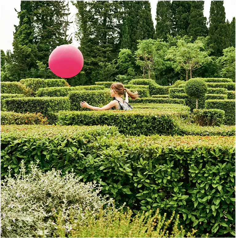 A little girl runs after a magenta balloon in a maze. (photo)