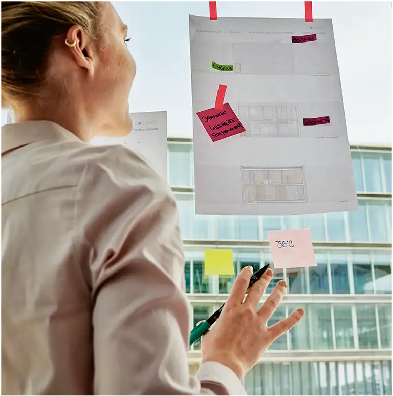 Two people standing in front of a window with different post-its on it (photo)