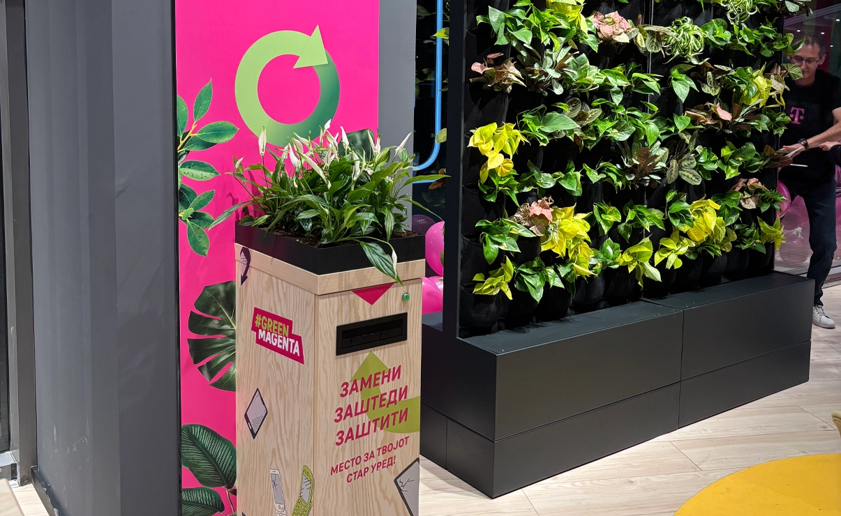 There is a return box next to a wall with many plants. The return box itself also has plants placed on top of it.