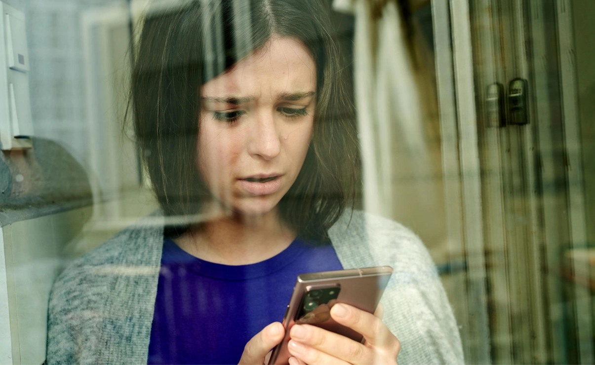A woman is looking with a concerned face on her phone screen.
