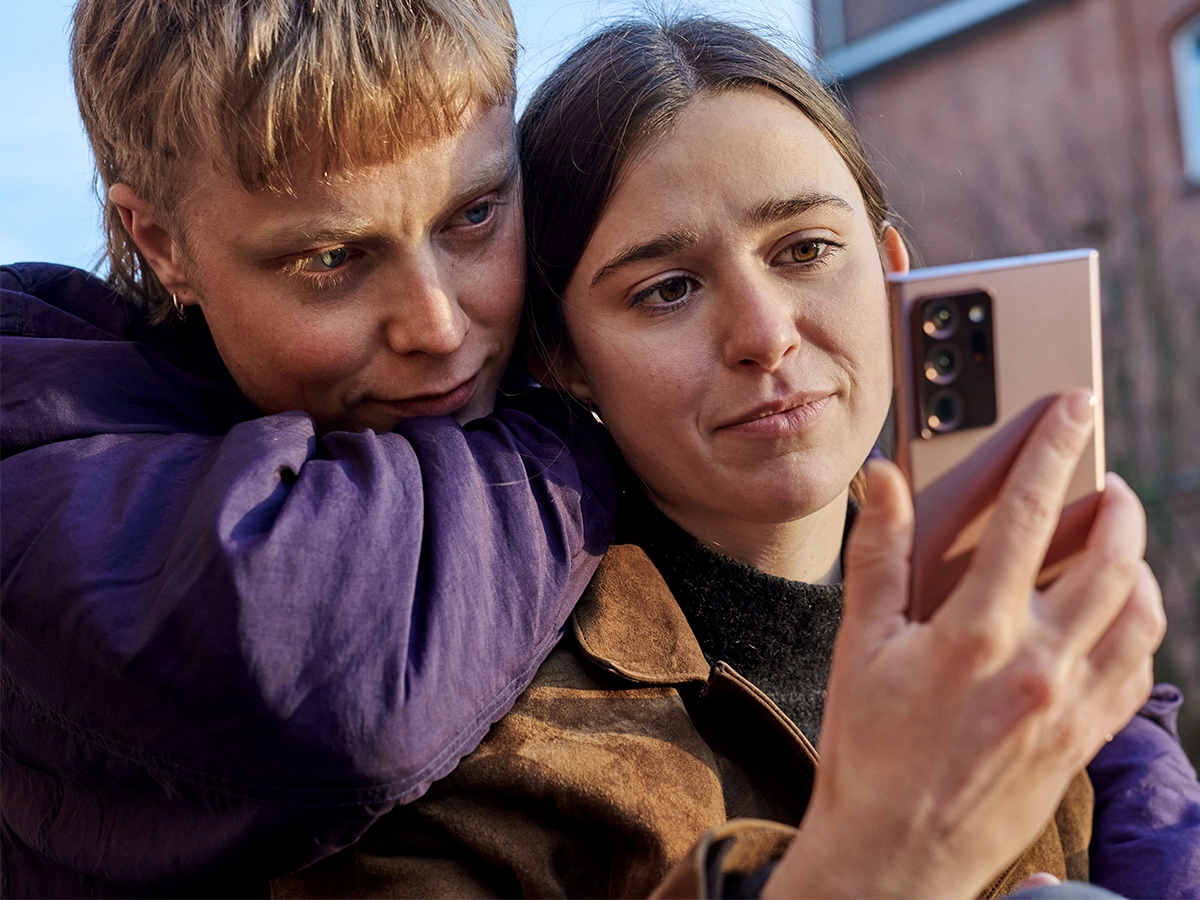 This is an image of two people looking at one phone, while standing close together.
