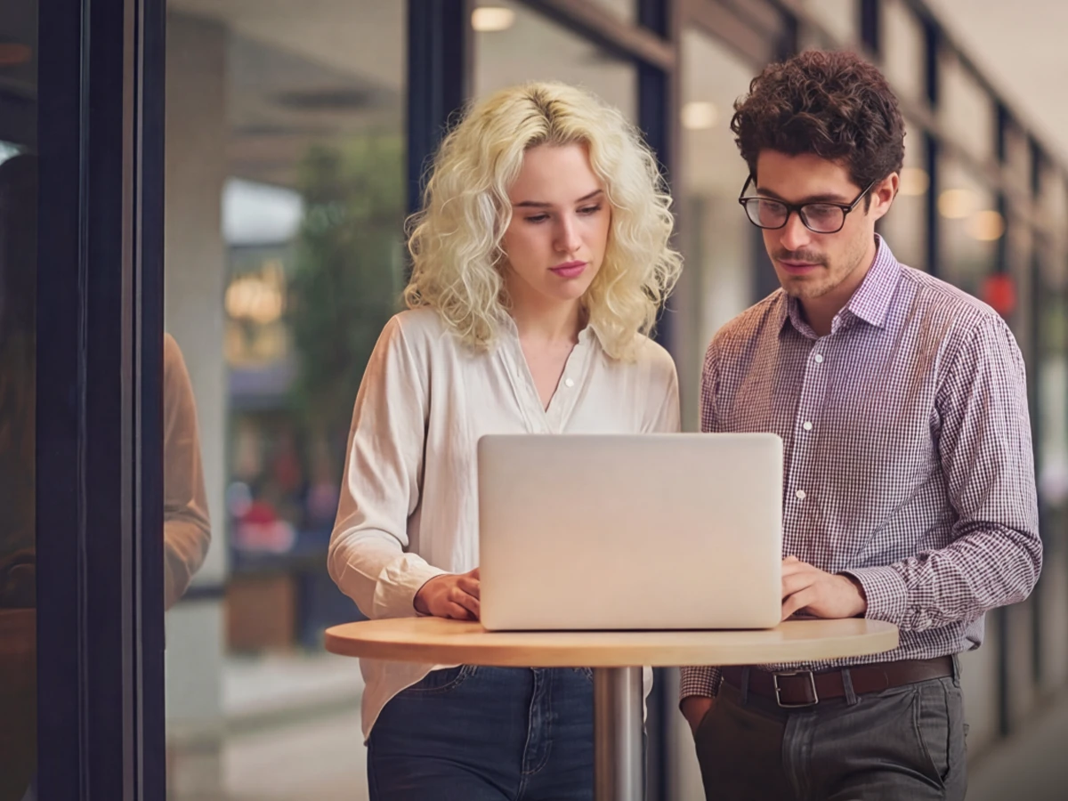 A woman and a man are standing at a desk and looking into a notebook. (Header Photo)