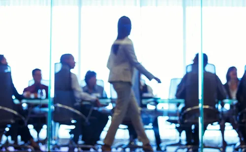 Meeting room, seated people, a woman walking